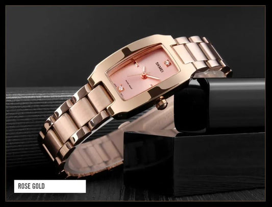 Rose gold watch on a reflective black surface with a dark background
