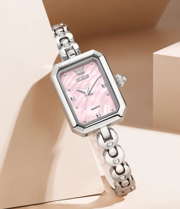Silver watch with a pink face on a beige background