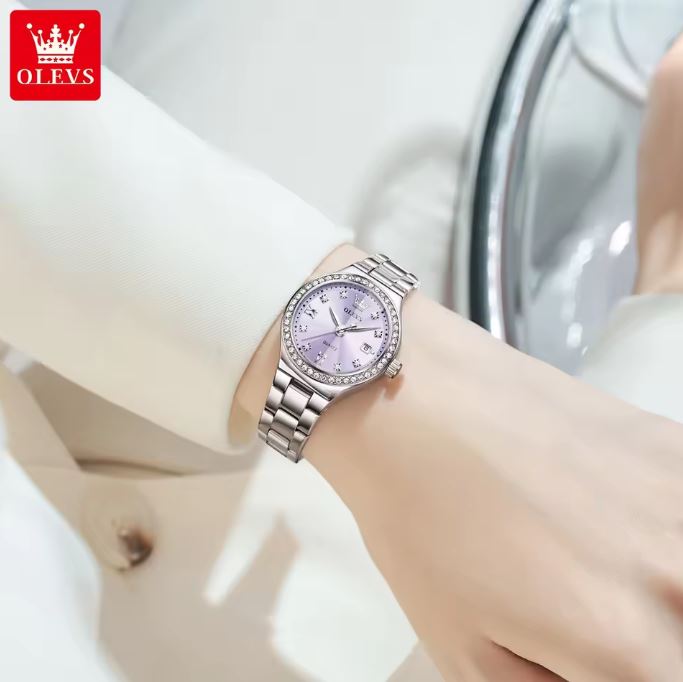 Silver watch with a purple face on a wrist, brand 'OLEVS' visible