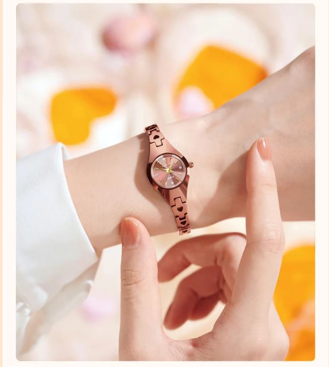 Rose gold watch on a wrist with a soft, blurred background
