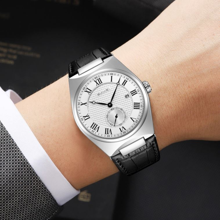 Luxury watch with black leather strap on a wrist against a dark background
