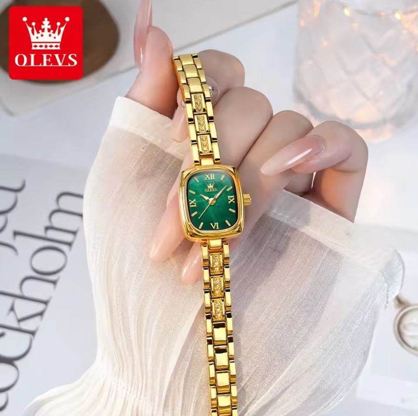 Gold watch with green face held by a hand, OLEVS brand visible