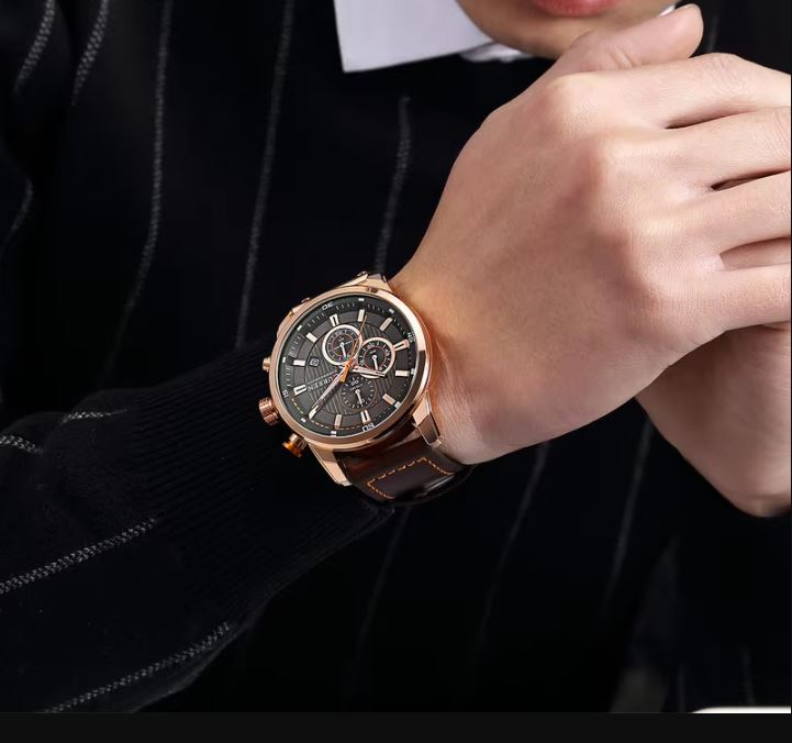 Rose gold watch on a person's wrist with a dark background