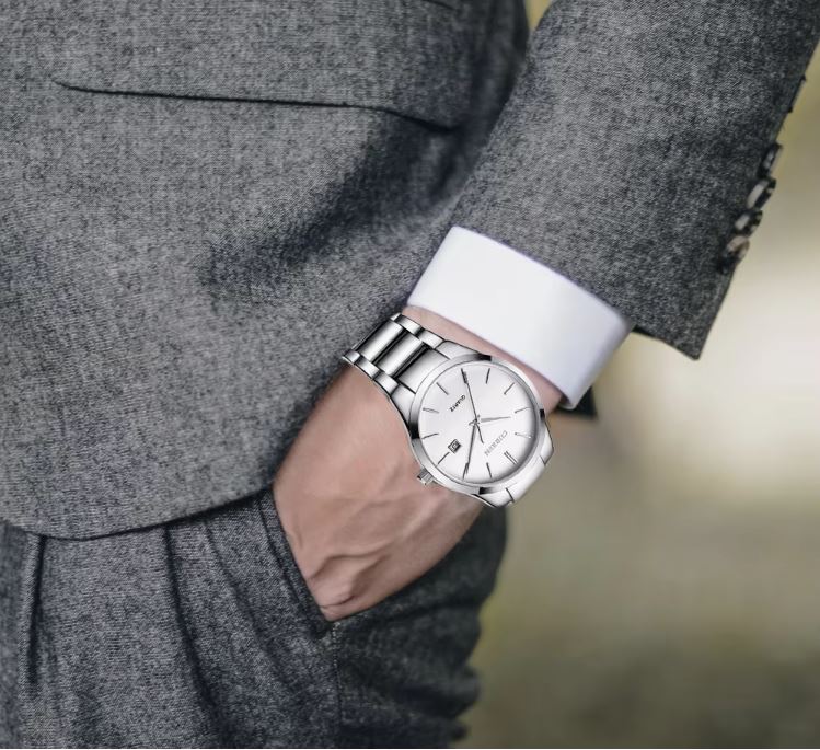Person wearing a silver wristwatch with a blurred background