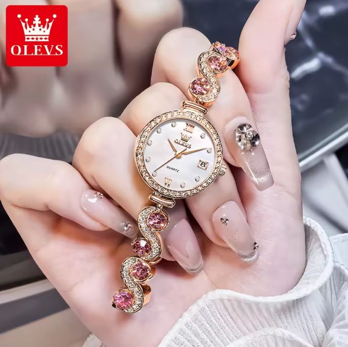 Luxury watch with pink gemstones held in a hand, OLEVS brand visible