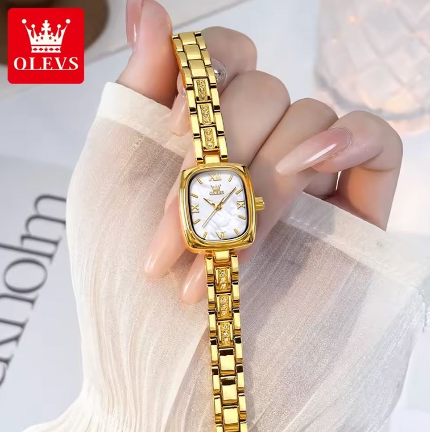 Gold wristwatch held by a hand with a light background, featuring the OLEVS brand.