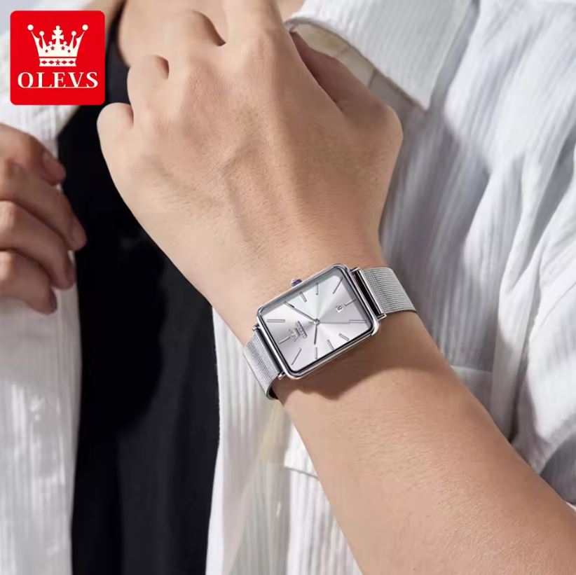Person wearing a silver watch with a white shirt, OLEVS logo visible