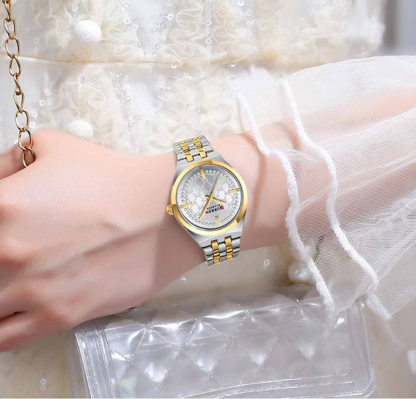 Gold and silver watch on a wrist with a white lace background