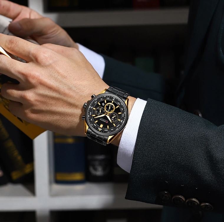 Person wearing a black and gold watch with a blurred background