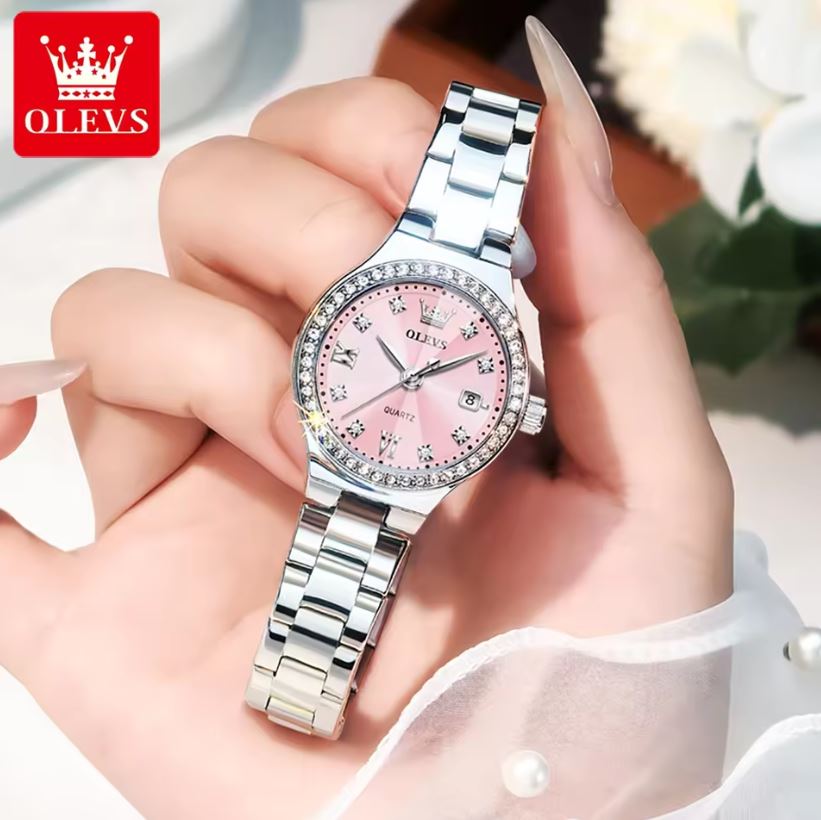 Silver watch with pink face held in a hand, OLEVS brand visible