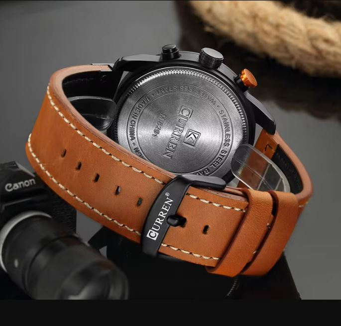 Watch with brown leather strap and visible brand name on a blurred background