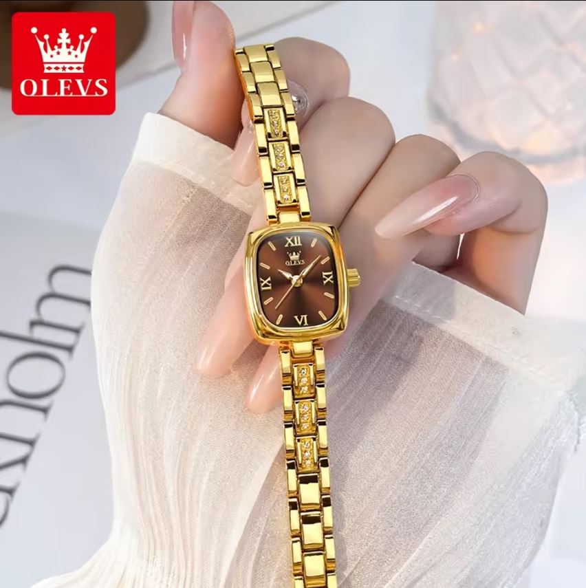 Gold wristwatch held by a hand with a blurred background