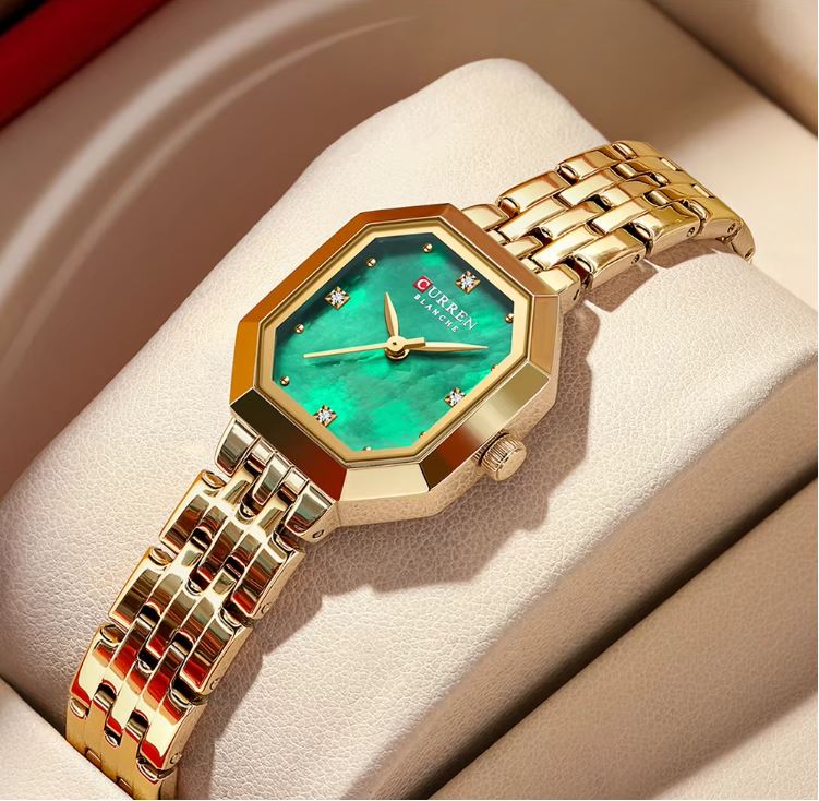 Gold wristwatch with a green face on a beige cushion