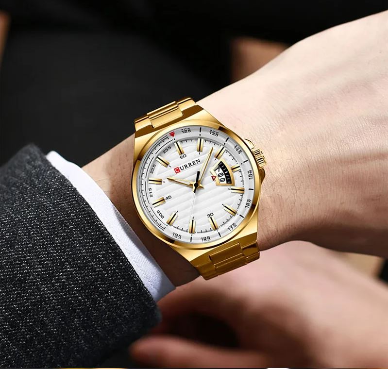 Gold wristwatch with a white face on a person's wrist, brand 'Curren' visible.