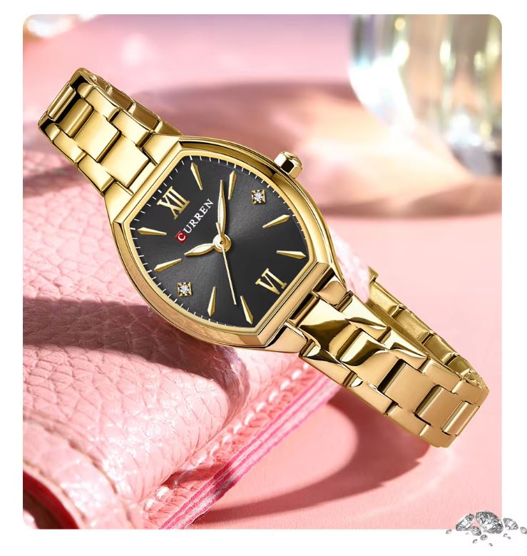 Gold wristwatch with black dial on a pink background