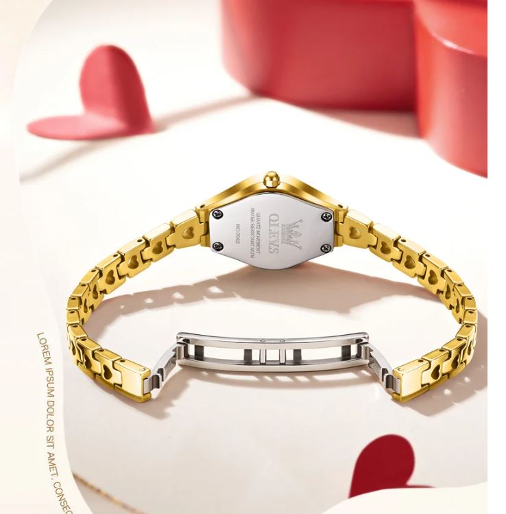 Gold bracelet on a white surface with red heart shapes in the background