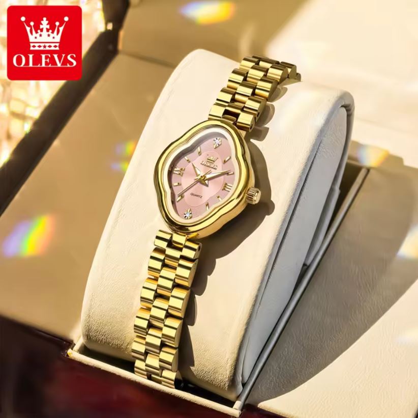 Gold wristwatch with pink face on a white cushion, brand 'OLEVS' visible