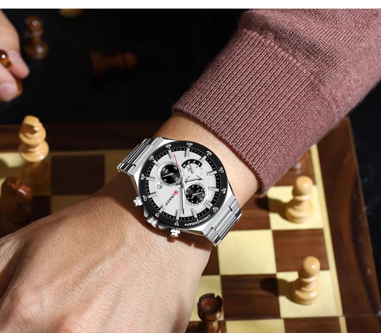 Person wearing a silver watch on a chessboard