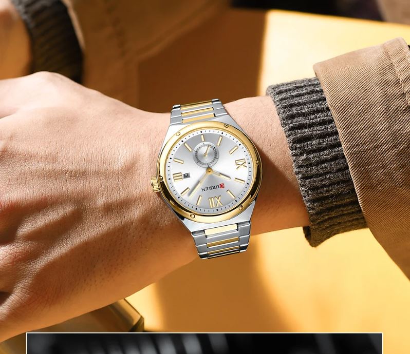 Gold and silver watch on a wrist with a blurred background
