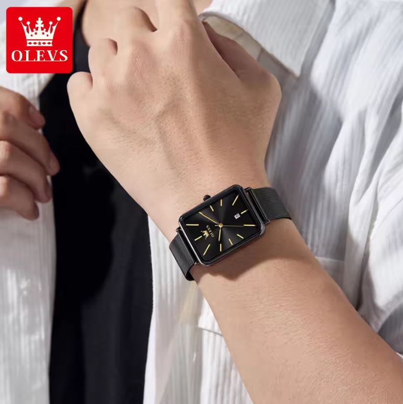 Person wearing a black wristwatch with a white shirt background, featuring the OLEVS brand logo.