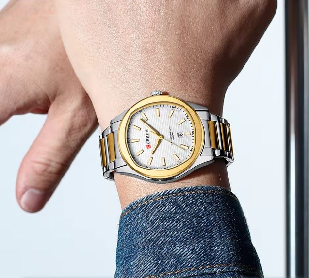 Gold and silver watch on a wrist with a blurred background