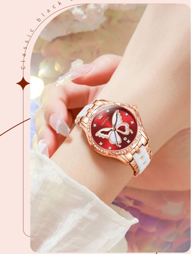 Wristwatch with red dial and butterfly design on a wrist, blurred background
