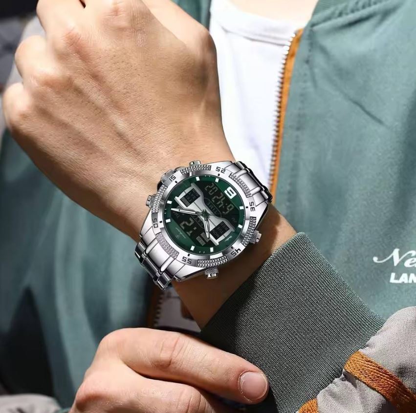 Close-up of a wrist wearing a silver and green watch with a blurred background