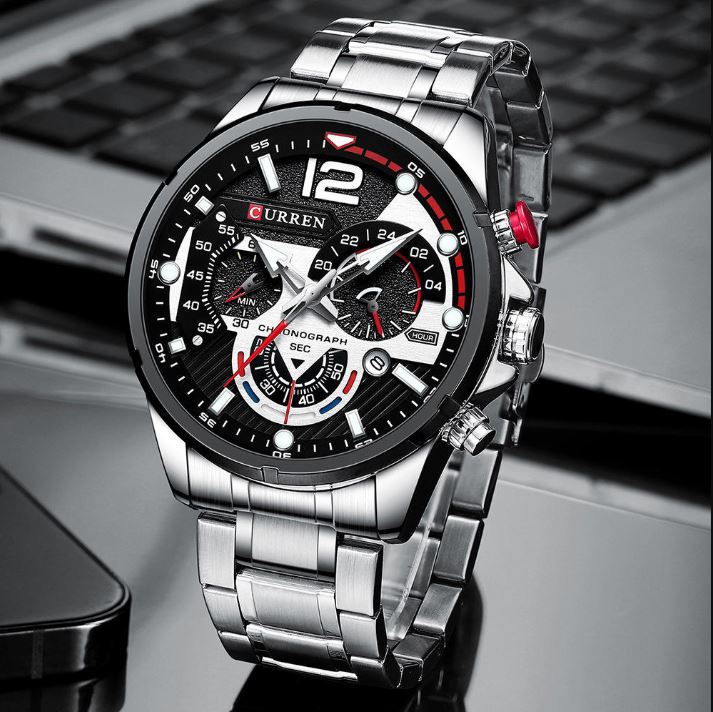 Silver wristwatch with a detailed face on a reflective surface