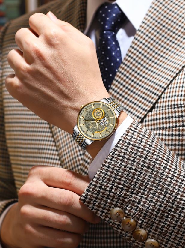 Close-up of a person wearing a detailed wristwatch on a checkered suit jacket.