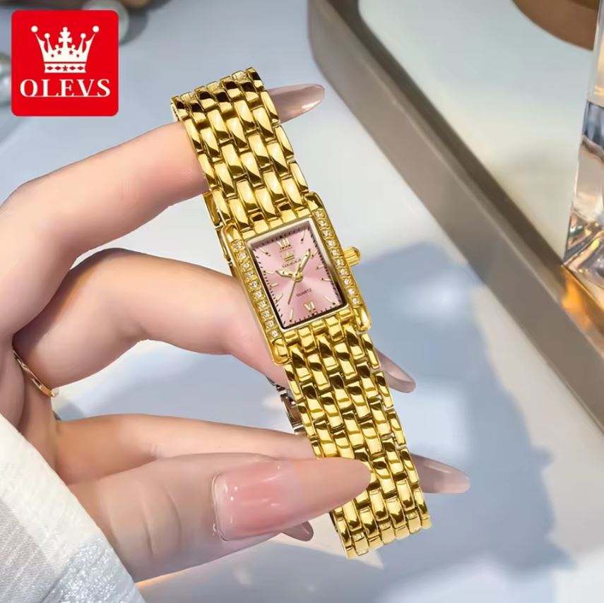 Gold watch with pink face held by a hand, OLEVS brand visible