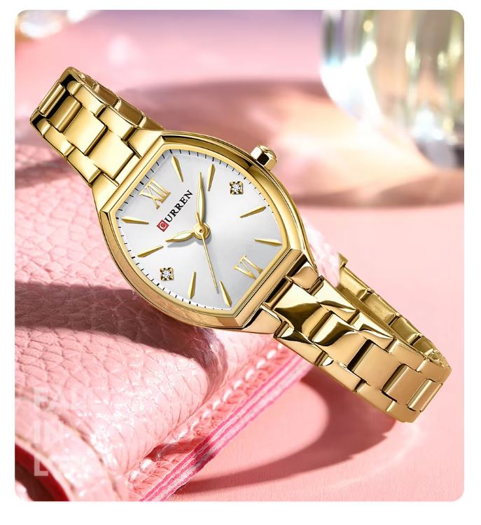 Gold wristwatch with a white face on a pink background