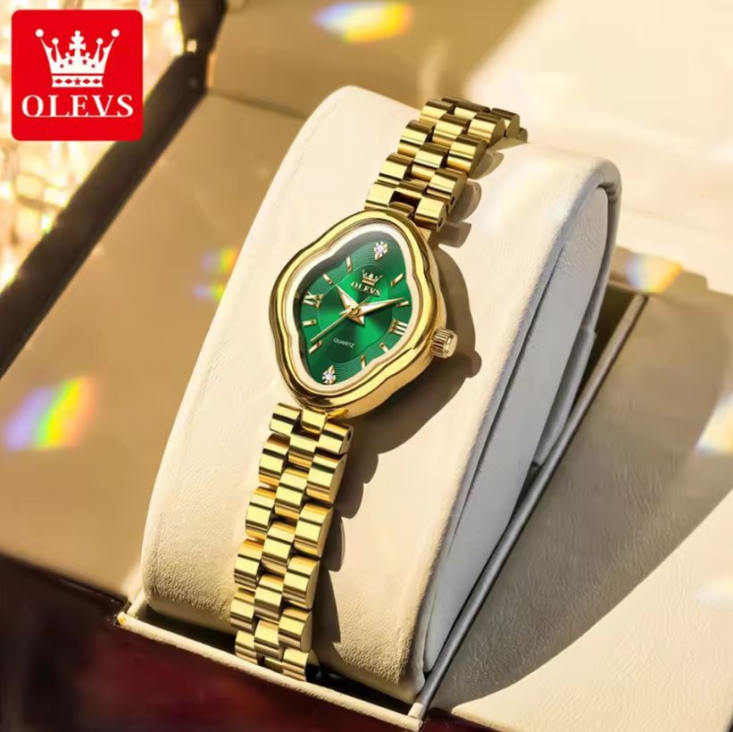 Gold wristwatch with green face on a white cushion, brand 'OLEVS' visible