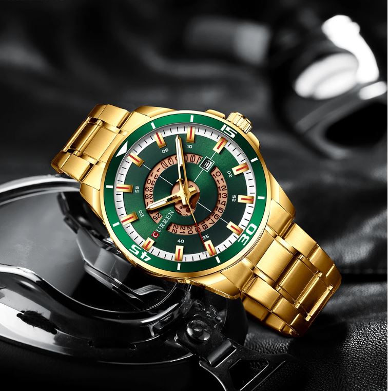 Gold wristwatch with a green face on a dark background