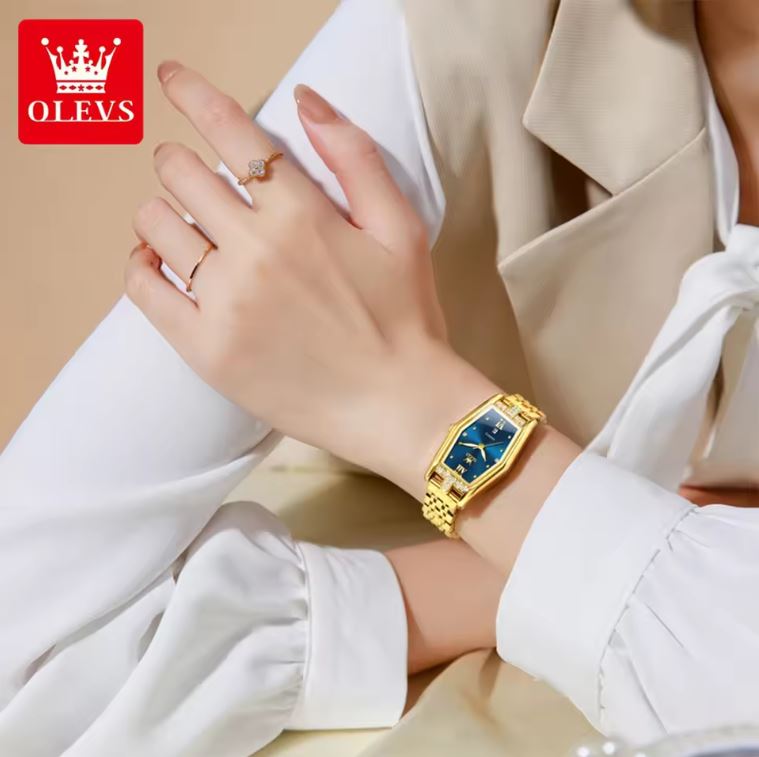 Gold watch on a wrist with a neutral background, featuring the OLEVS brand.
