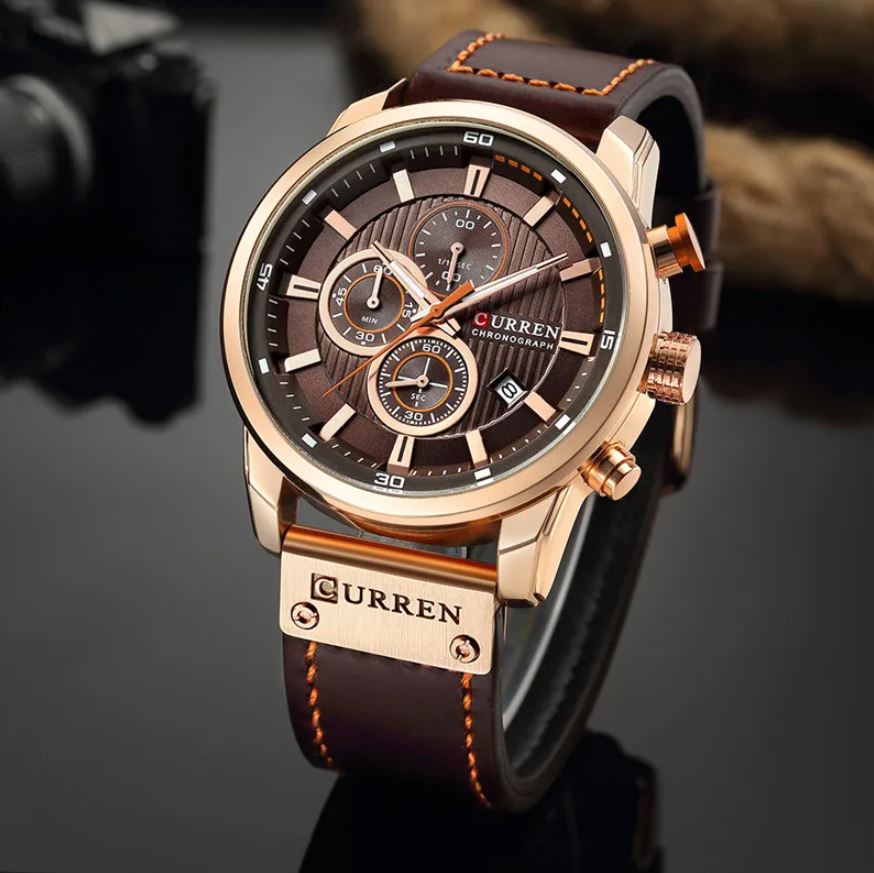 Curren watch with brown leather strap and rose gold case on a dark background