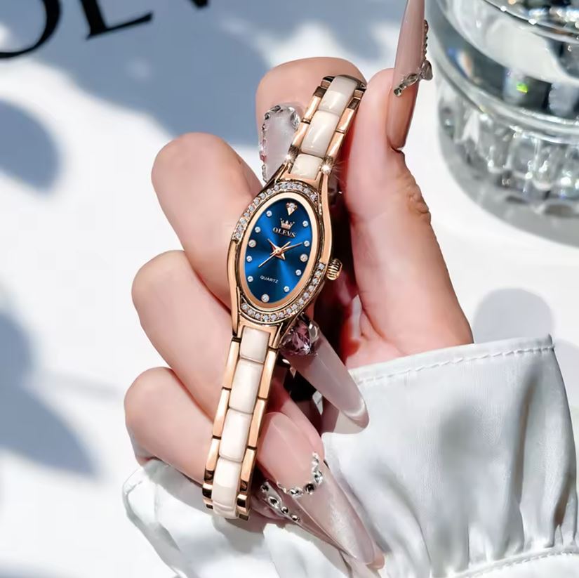 Hand holding a rose gold and blue watch with a blurred background