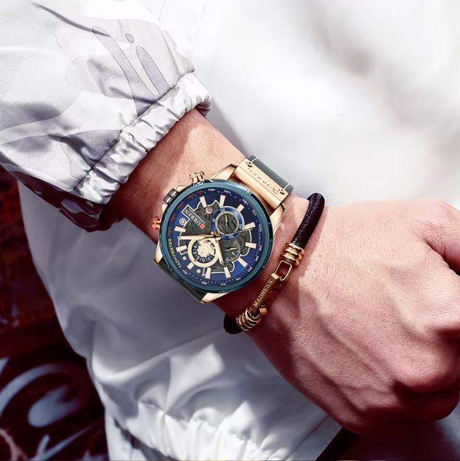Close-up of a wrist wearing a gold and blue watch with a blurred background