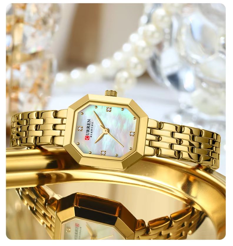 Gold wristwatch with a decorative face on a blurred background