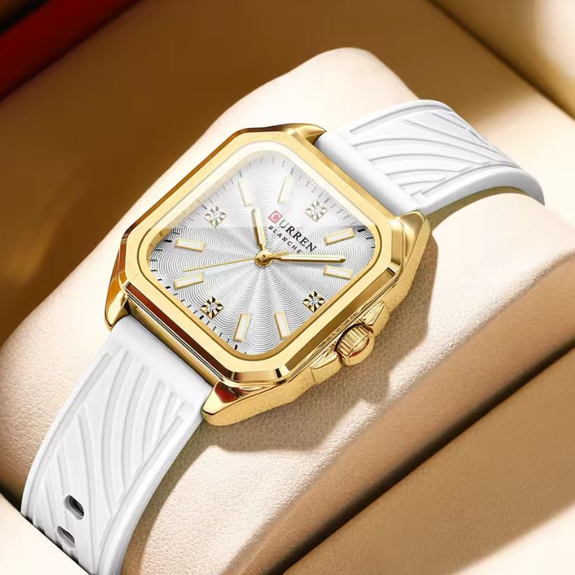 Gold and white watch on a wrist with a beige background