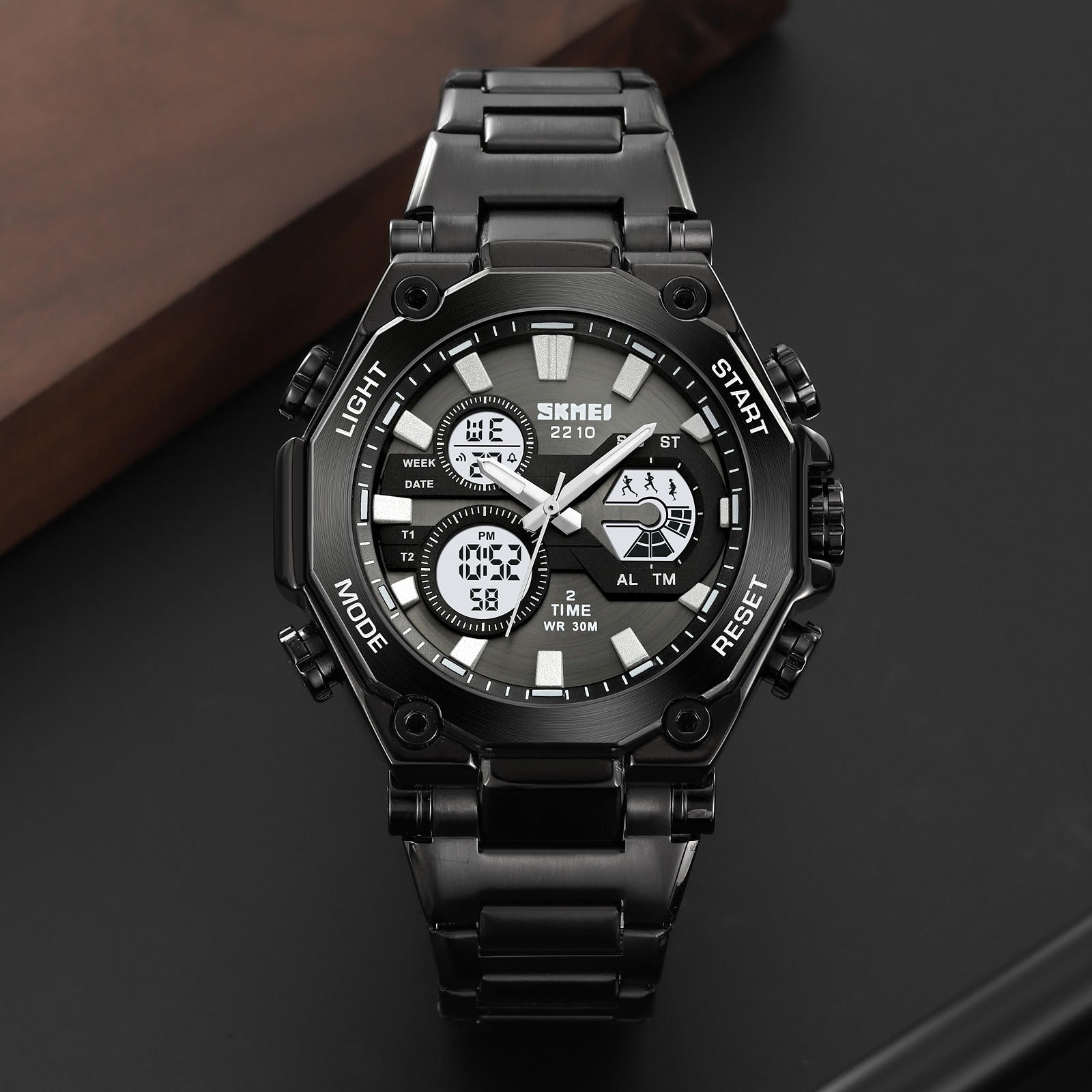 Black digital wristwatch with metal strap on a dark background