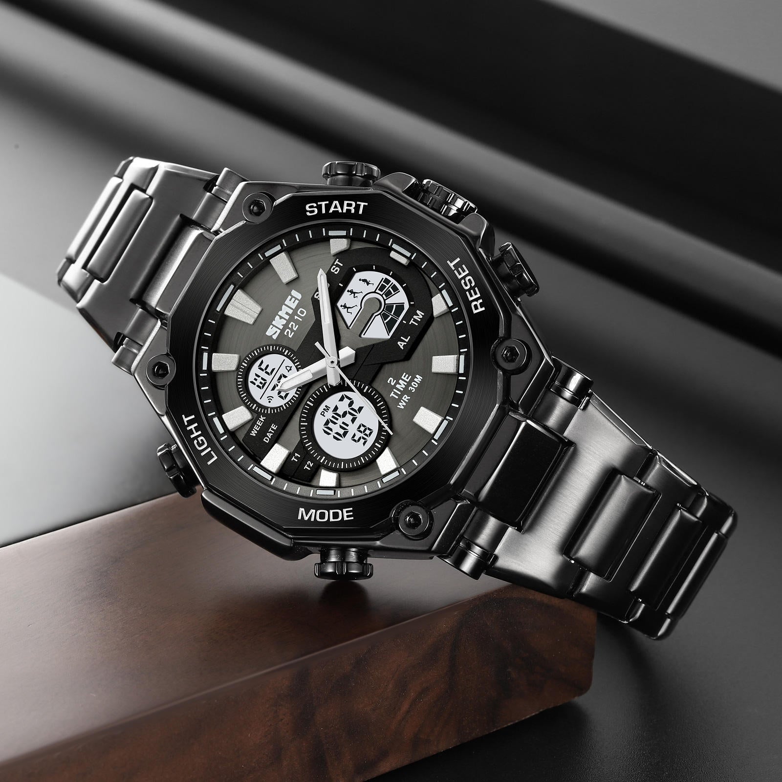 Black wristwatch with metal strap on a dark background