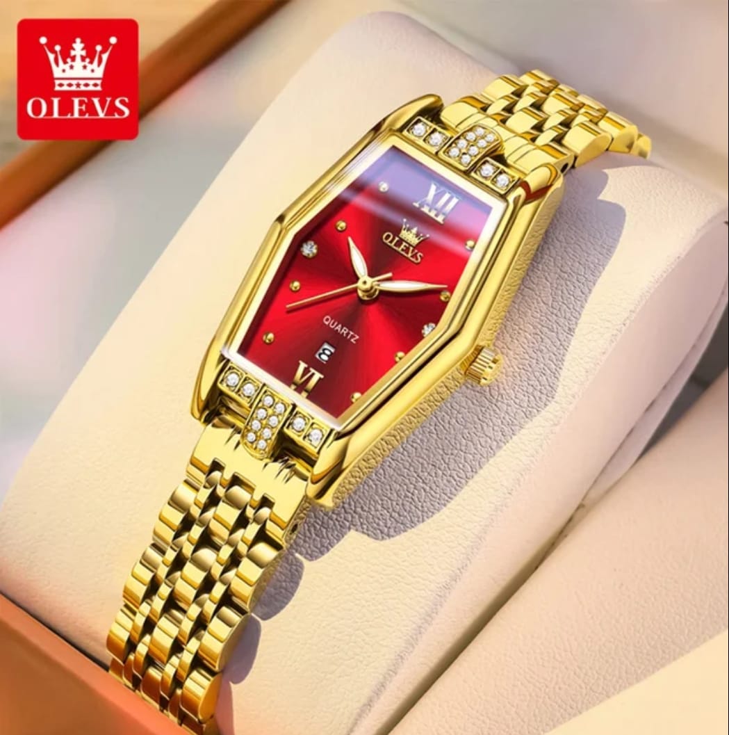 Gold wristwatch with red face on a beige cushion, brand 'OLEVS' visible