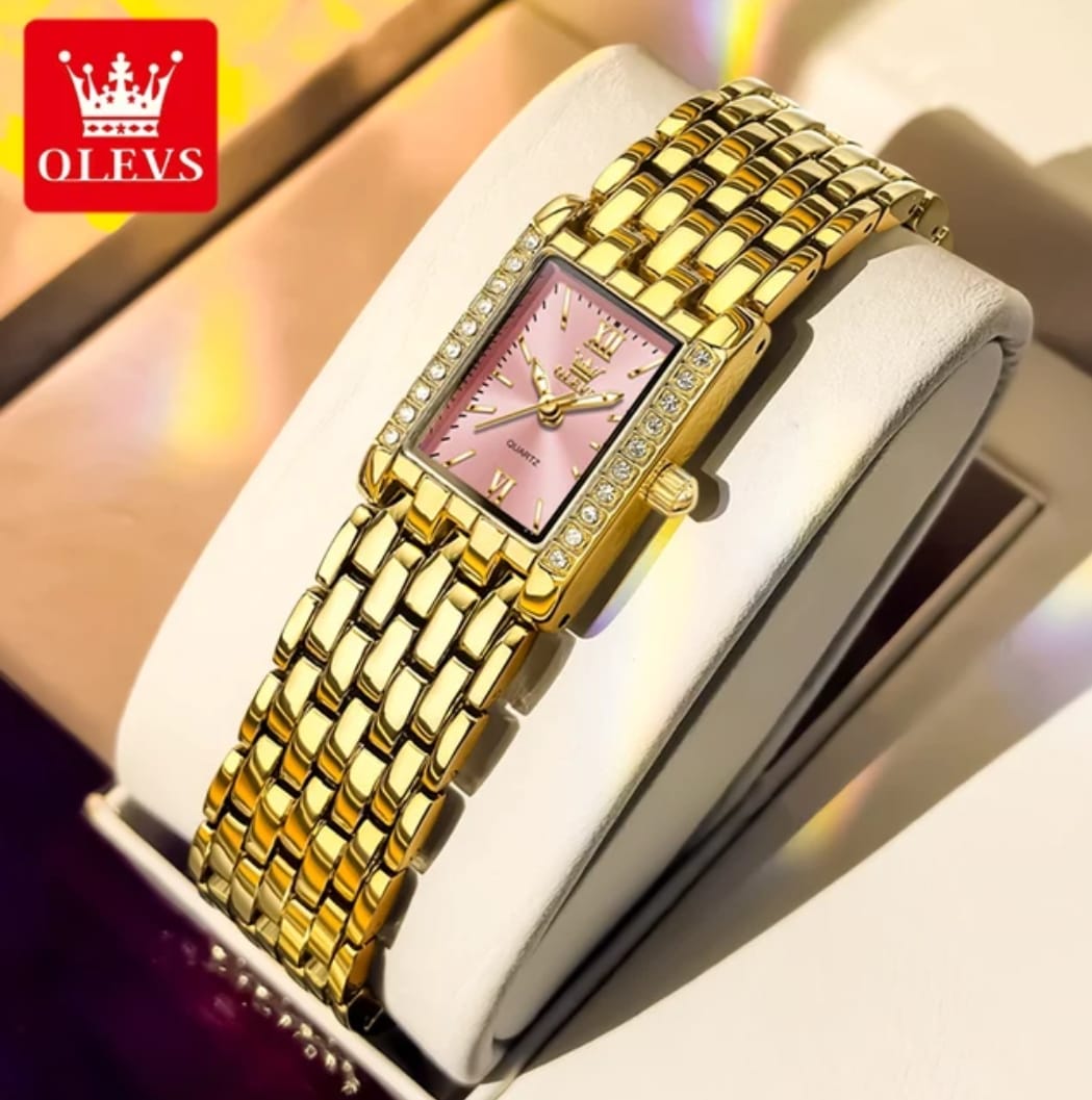 Gold wristwatch with pink face on a white cushion, brand 'OLEVS' visible.