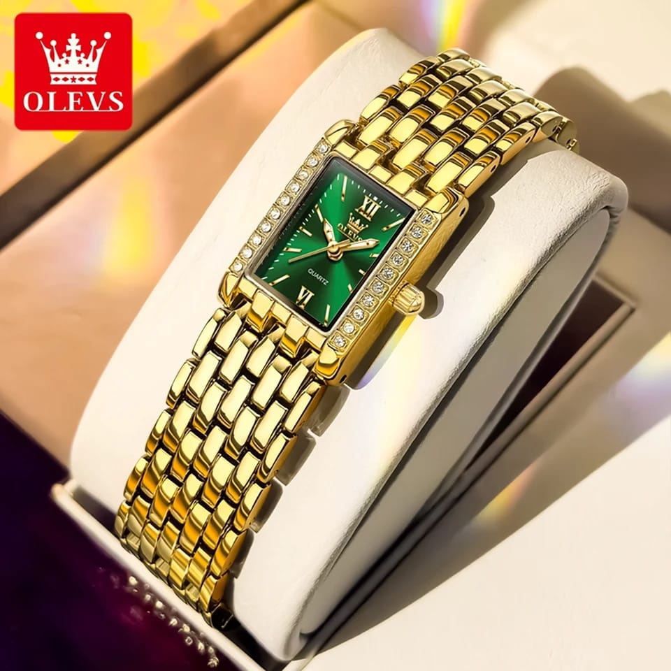Gold wristwatch with green face on a white cushion, brand 'OLEVS' visible.