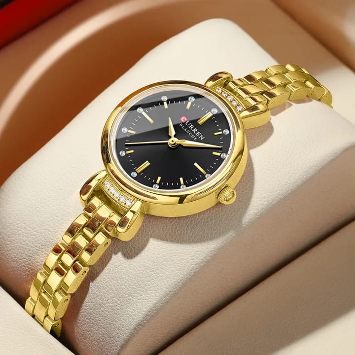Gold wristwatch with black dial on a soft surface
