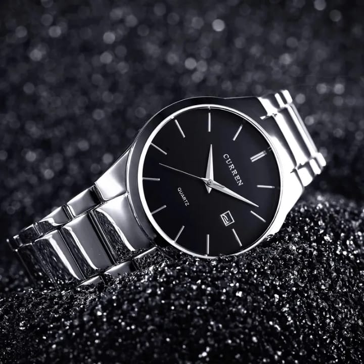 Silver watch with black dial on a dark textured background