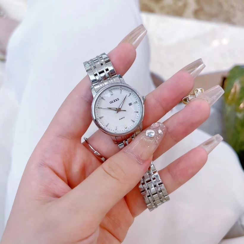Hand holding a silver watch with a blurred background