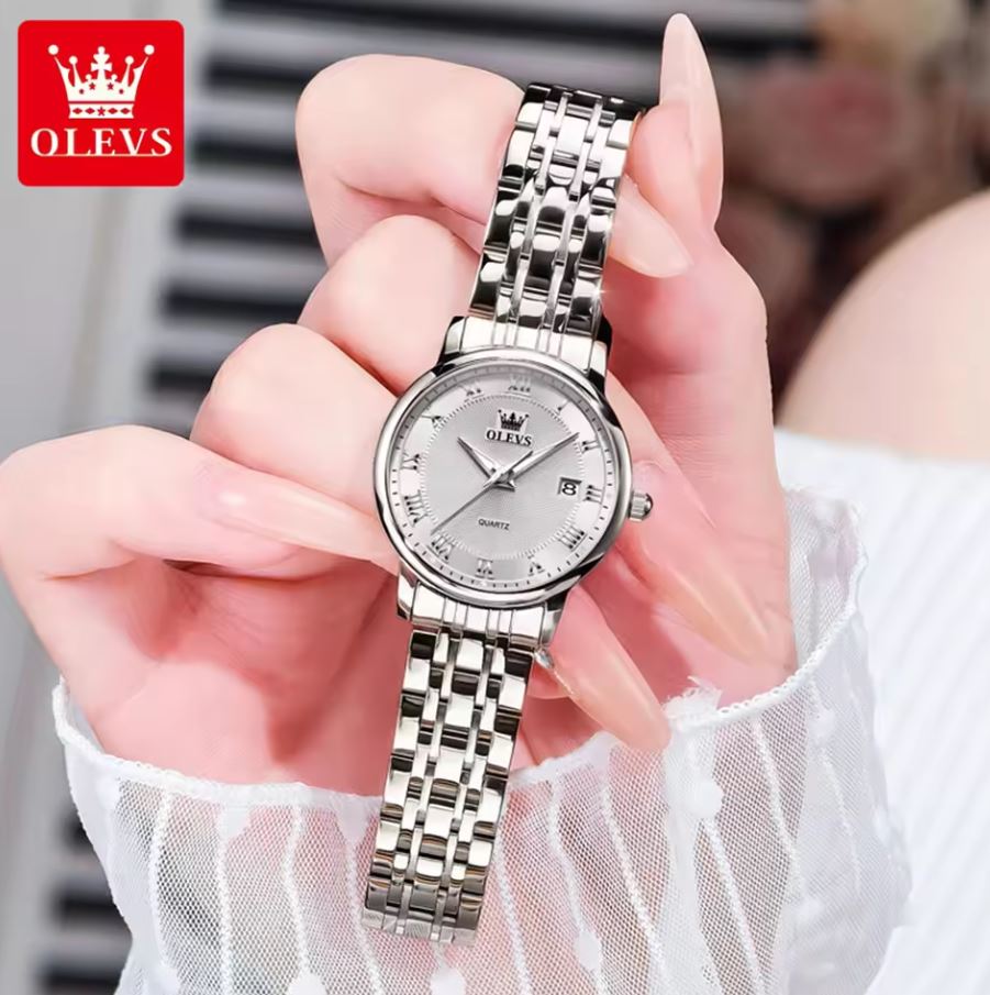 Silver watch held by a hand with OLEVS branding in the corner.