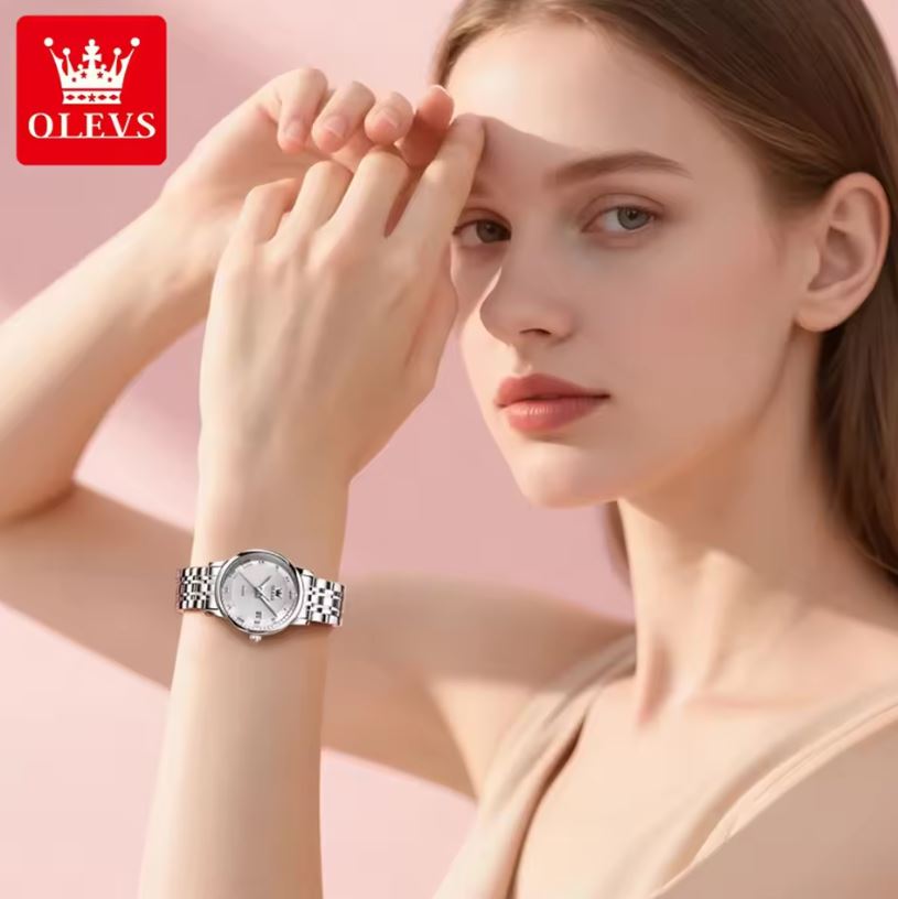 Woman wearing a silver watch with a pink background and OLEVS logo.