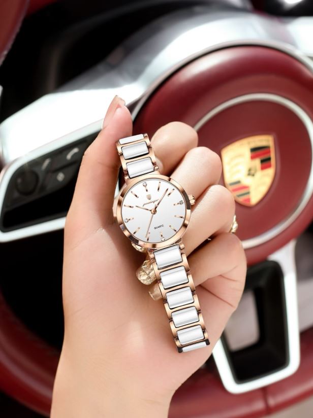 Hand holding a watch with a car's steering wheel and emblem in the background
